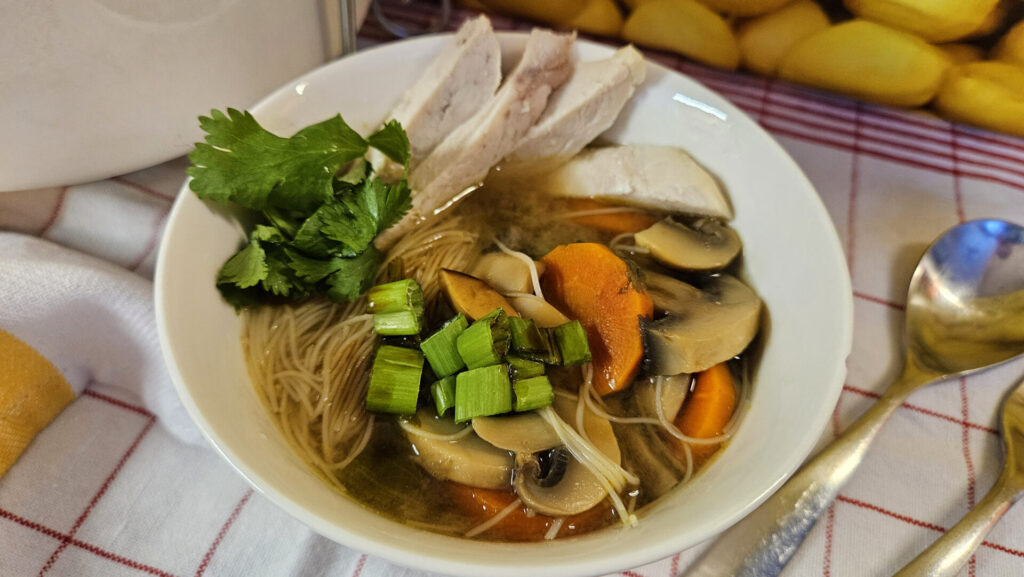 How To Make Pho Style Soup garnished with chicken, cilantro and green onions